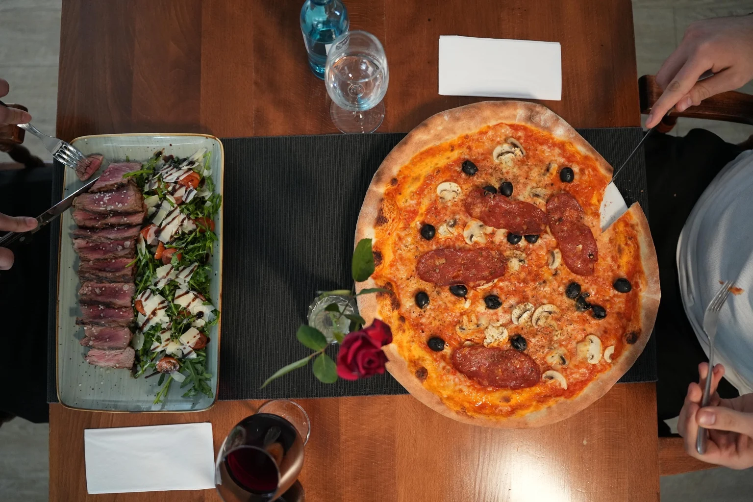 Pizza und Fleischgericht auf einem gedeckten Tisch bei Alberto